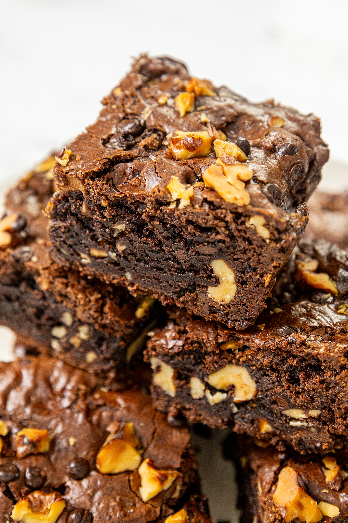 Fudgy chocolate walnut brownies stacked on a plate, showing rich chocolate texture and chunks of walnuts inside.