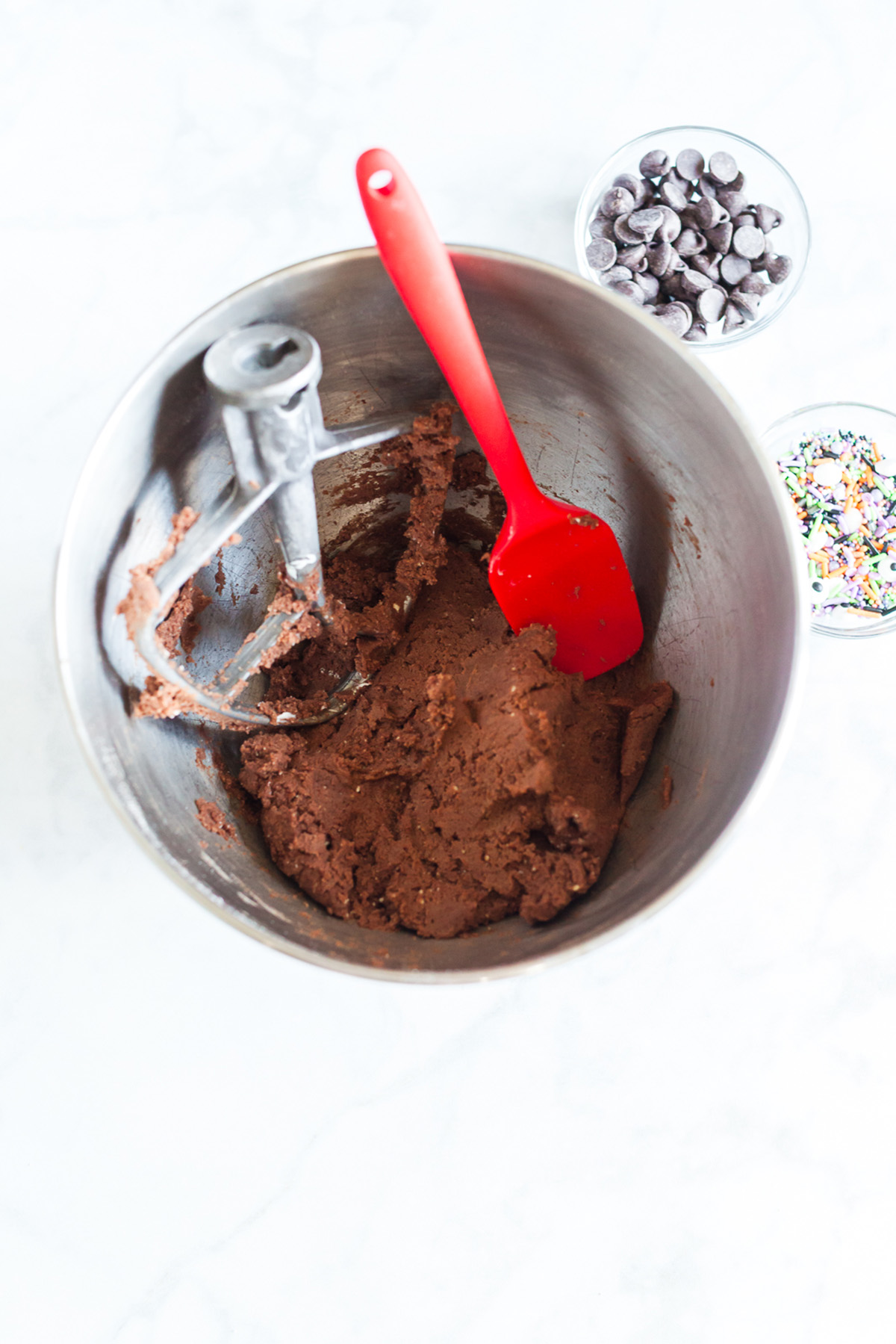Mixing bowl with chocolate cookie dough and a spatula, ready to add sprinkles and chocolate chips.