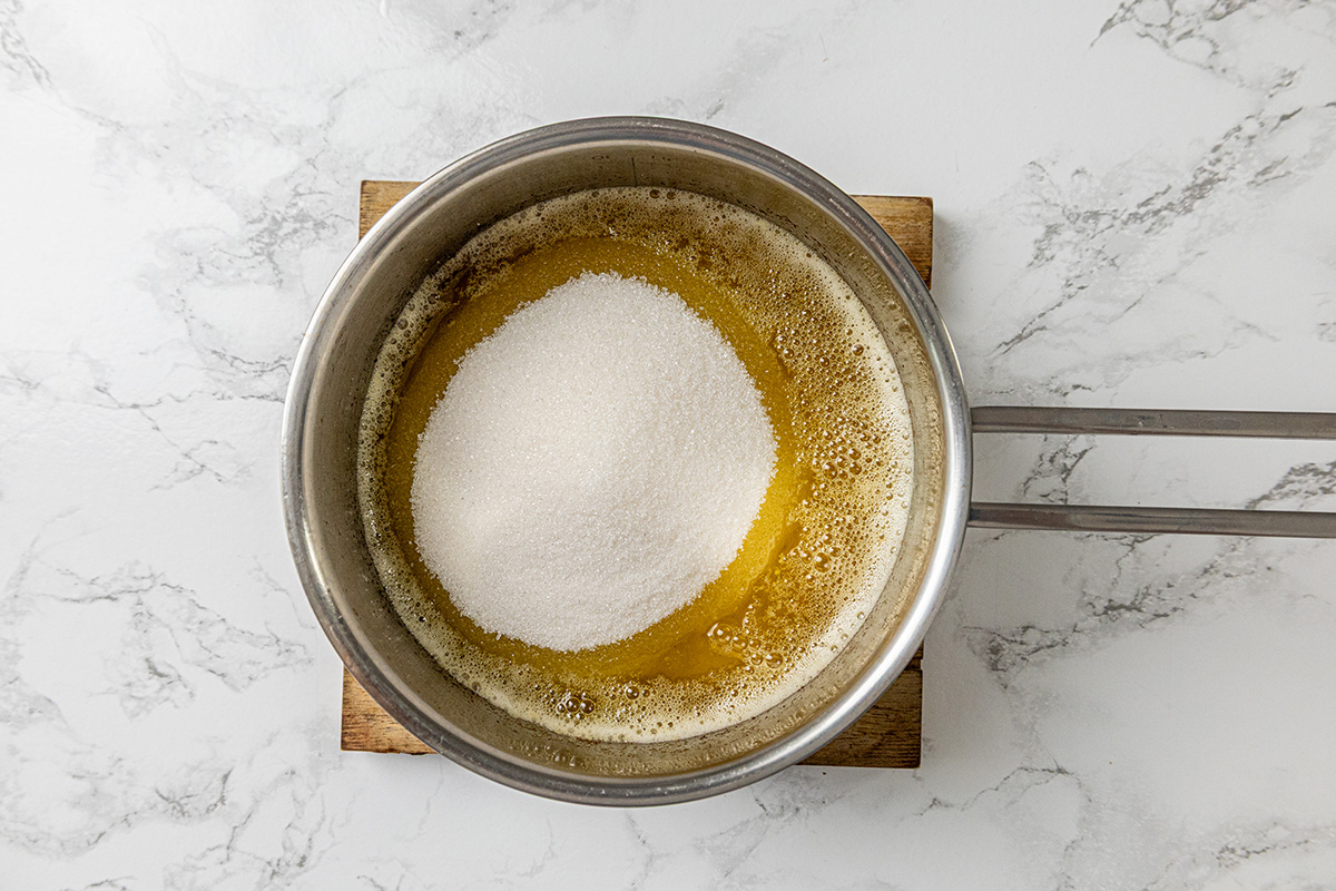 Granulated sugar sprinkled into a saucepan of browned melted butter.