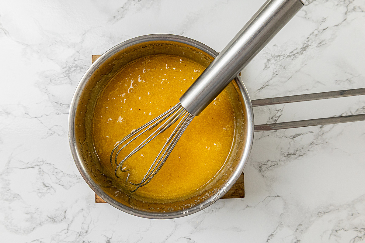 Whisk combining melted butter, sugar, and eggs into a smooth golden mixture for brownies