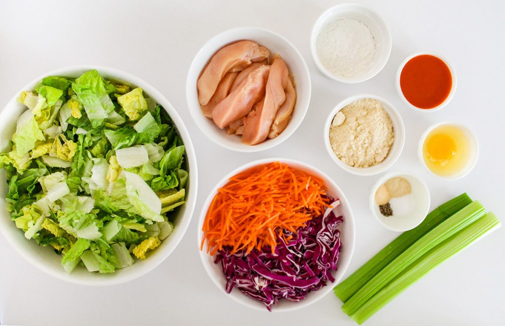 Lettuce, chicken tenders, buffalo sauce, vegetables on the counter.