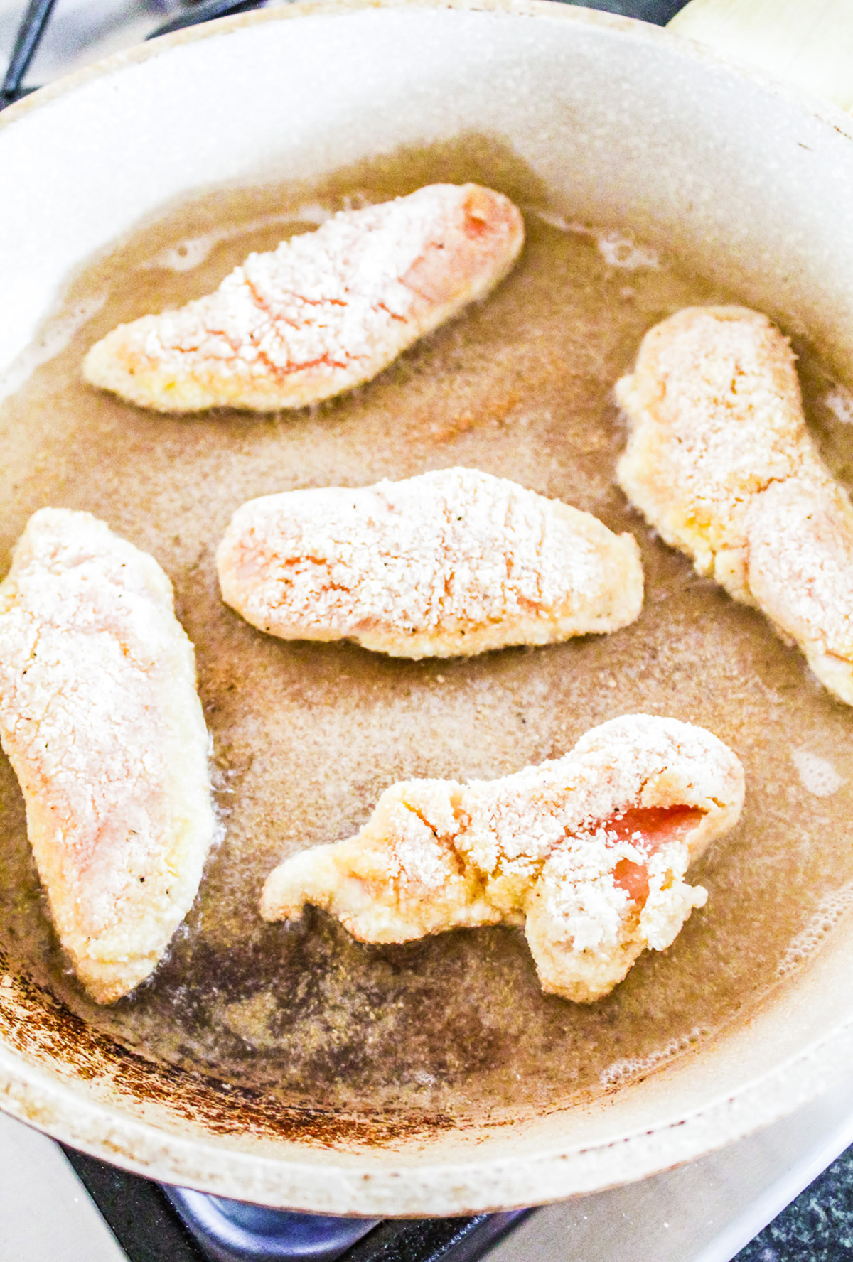 Pan frying chicken tenderloins in a skillet.