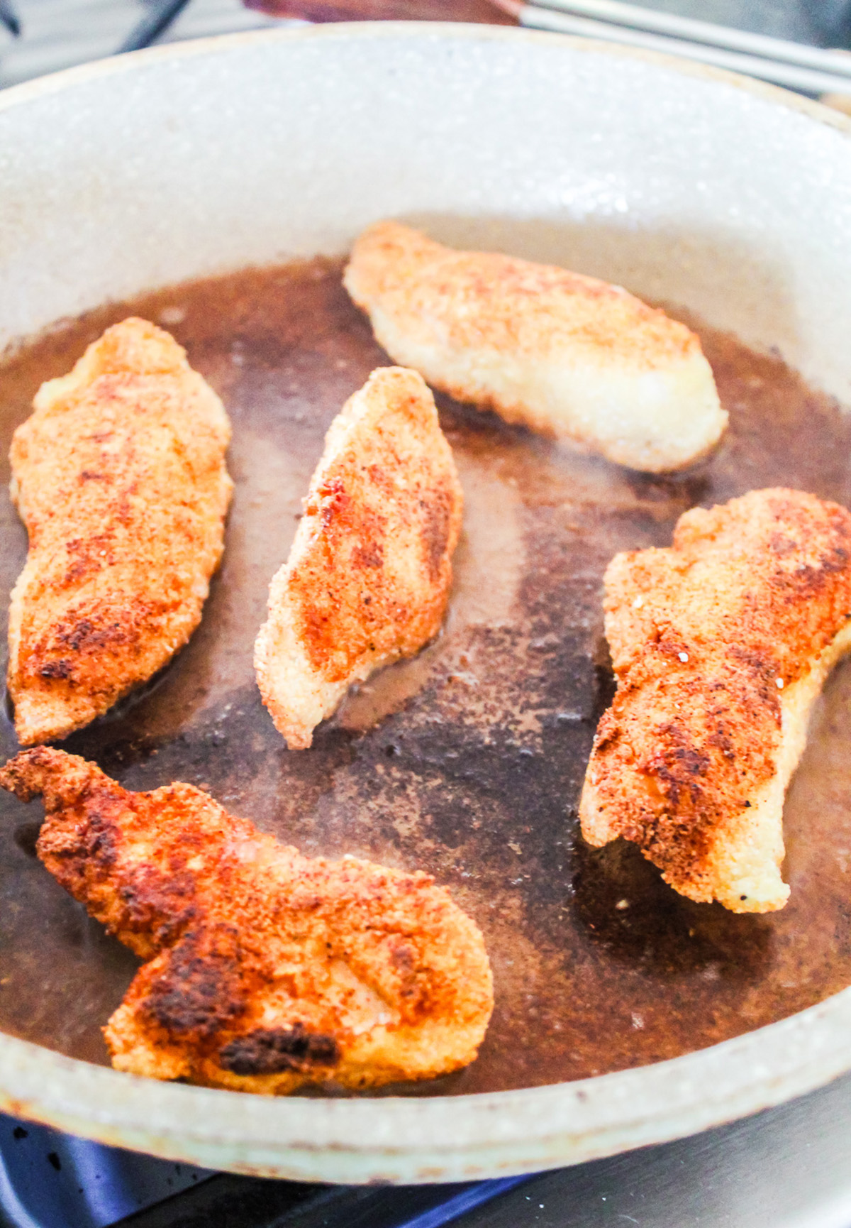 Pan frying chicken tenderloin.
