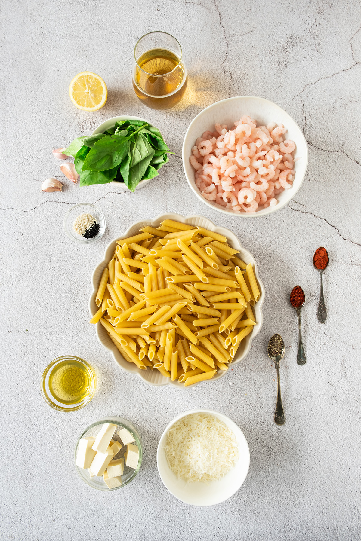 Pasta, shrimp, basil, garlic on the counter.