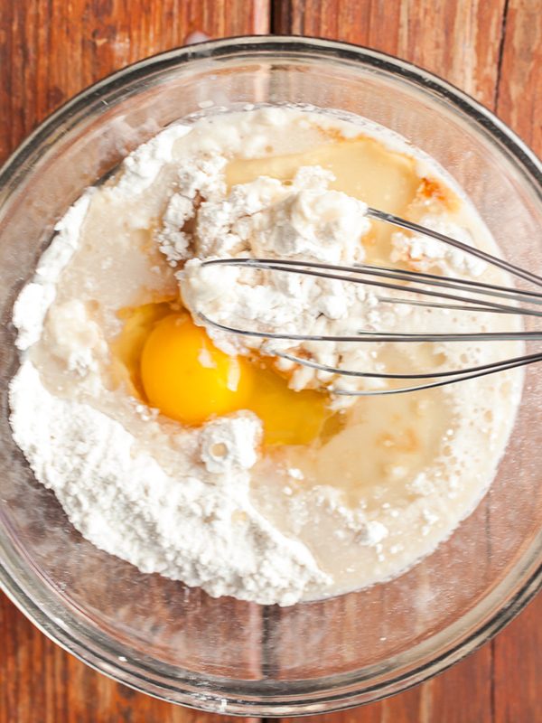 Flour, egg, oil and vanilla being whisked in a bowl for mini waffles.