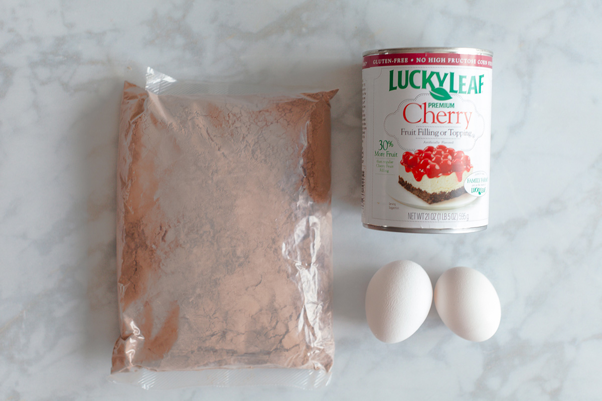 Brownie mix, cherry pie filling and two eggs on the counter for cherry brownies with brownie mix.