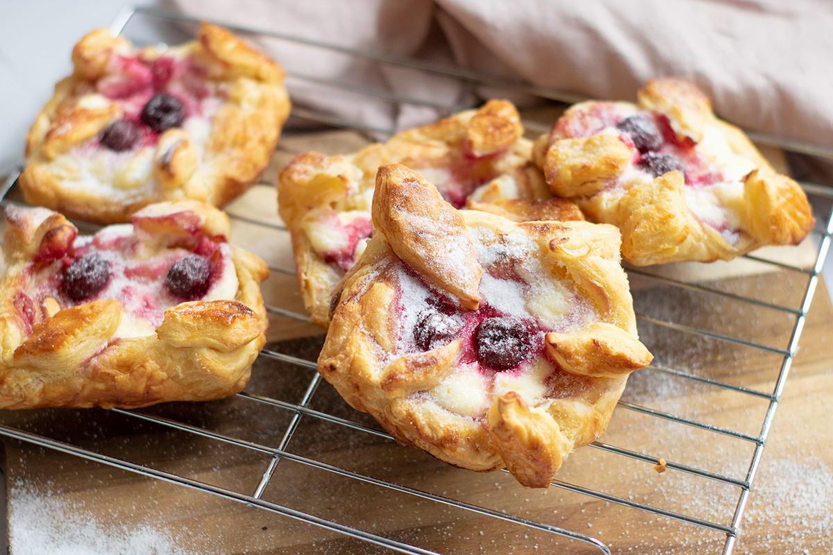 Cherry danish with puff pastry on wire rack.