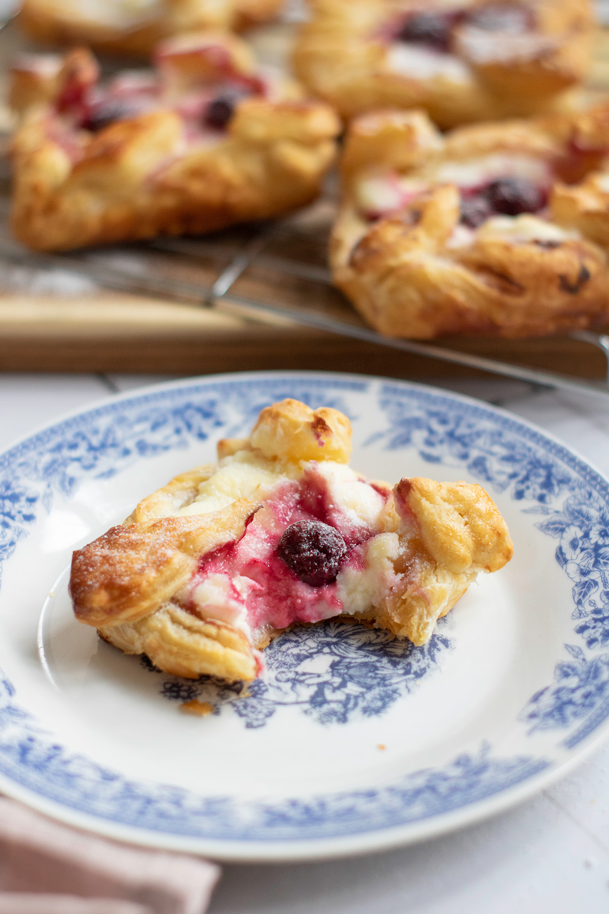 Cherry danish on a plate with a bite missing.