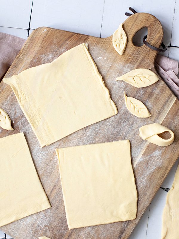 Puff pastry rolled out and cut into squares on a cutting board.
