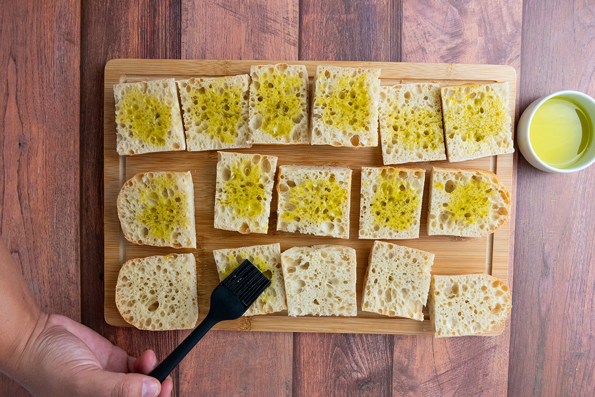 Brushing sliced bread with olive oil.
