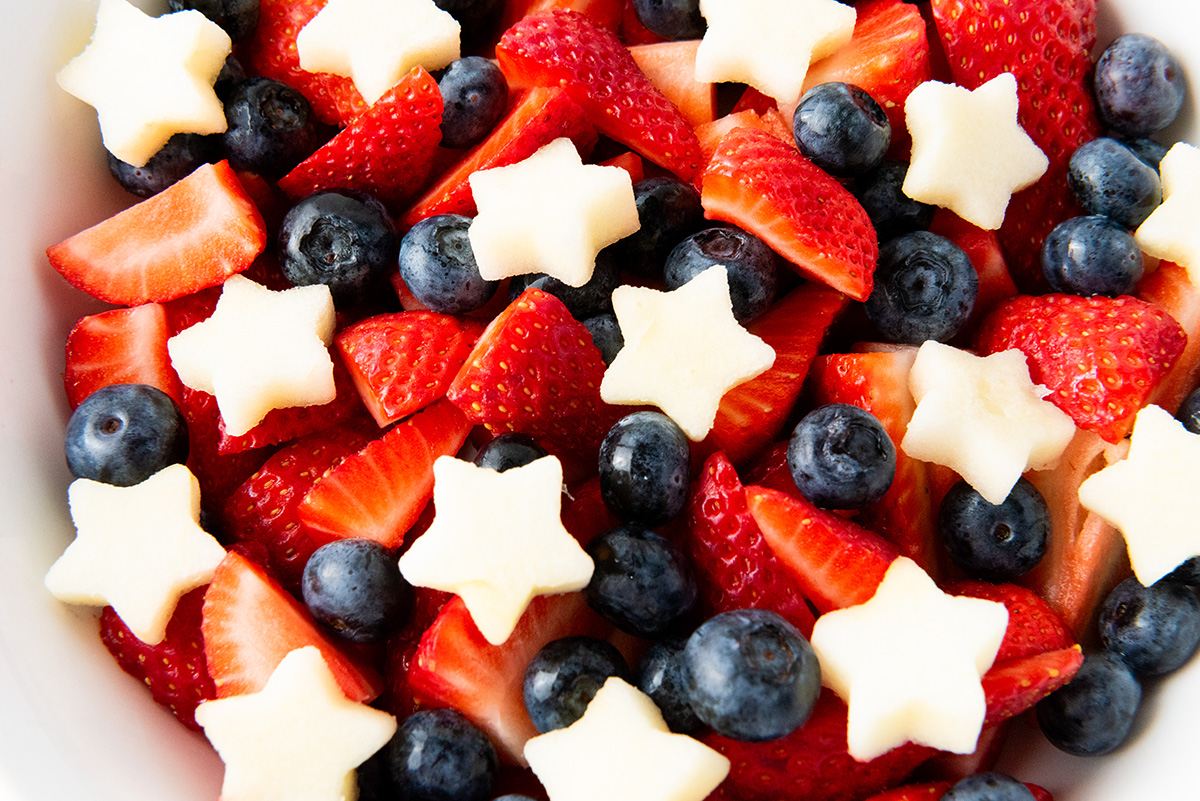 Close-up of patriotic fruit salad with vibrant strawberries, blueberries, and apple stars.