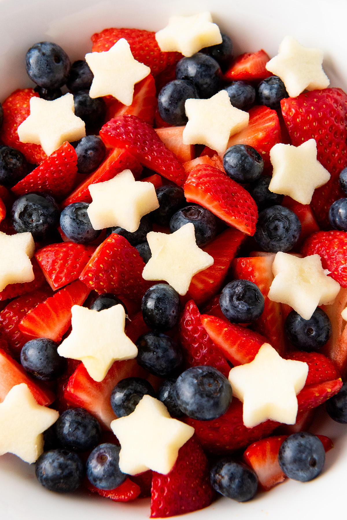 Close-up of patriotic fruit salad with vibrant strawberries, blueberries, and apple stars.