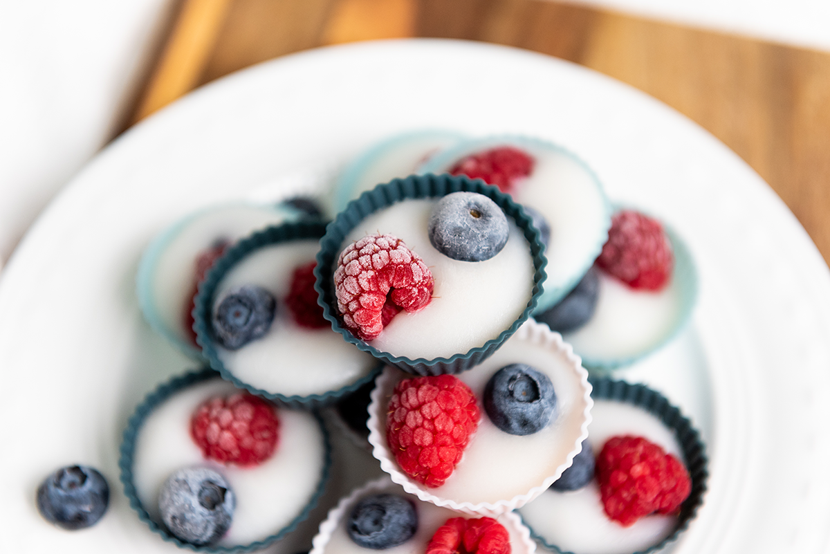 Zoomed-in shot of frozen yogurt bites with frosty berries on top, stacked in silicone cups.