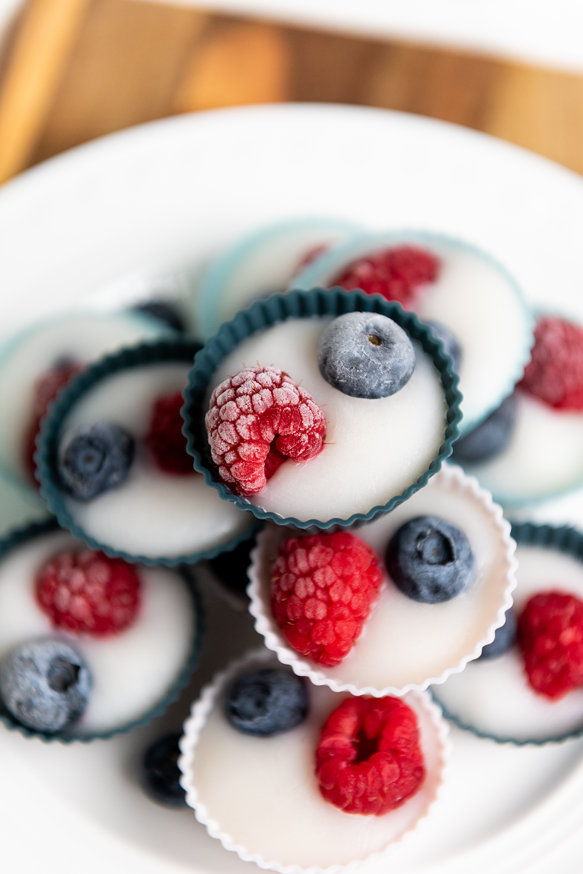 Zoomed-in shot of frozen yogurt bites with frosty berries on top, stacked in silicone cups.
