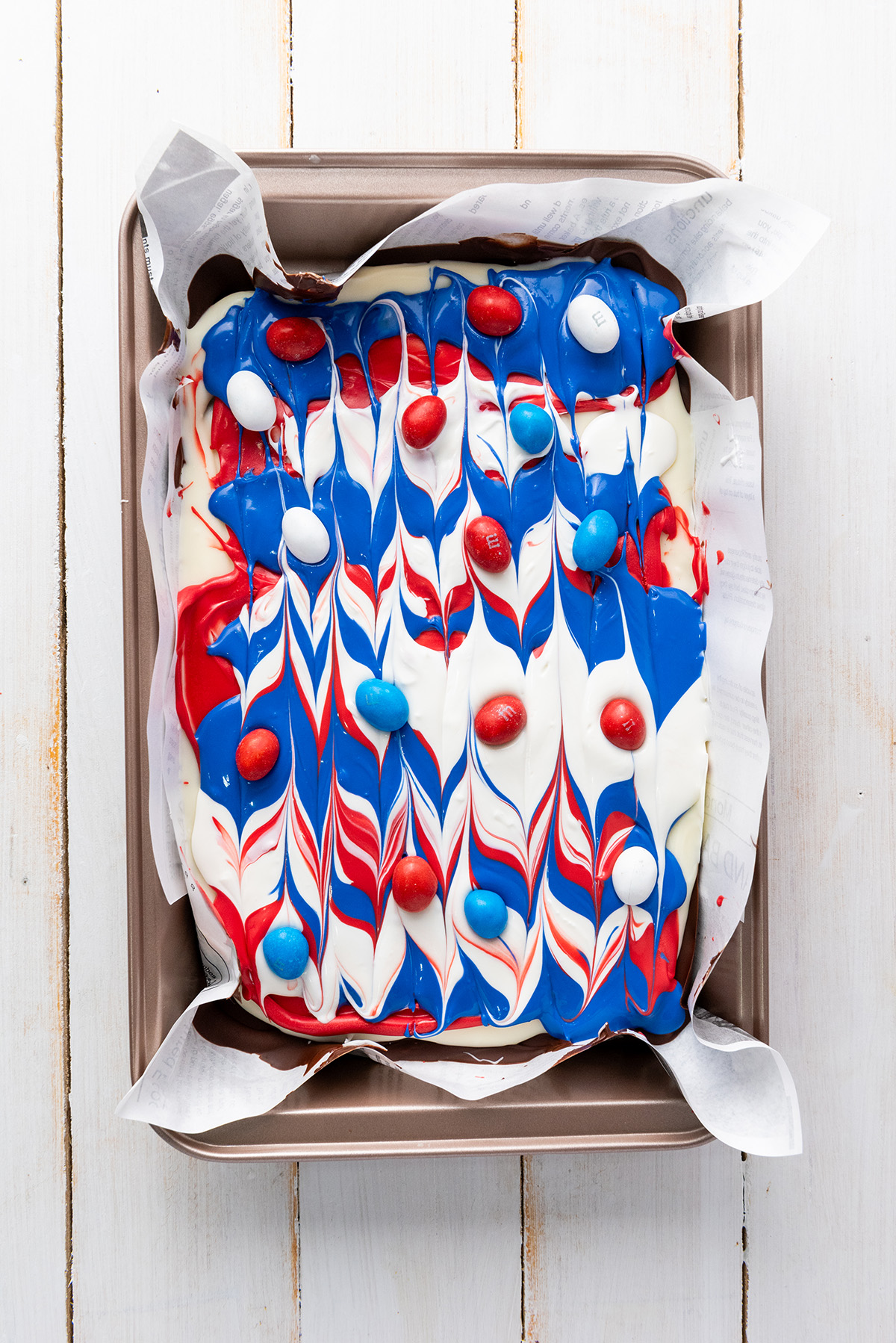Garnishing patriotic bark with M&M candy.
