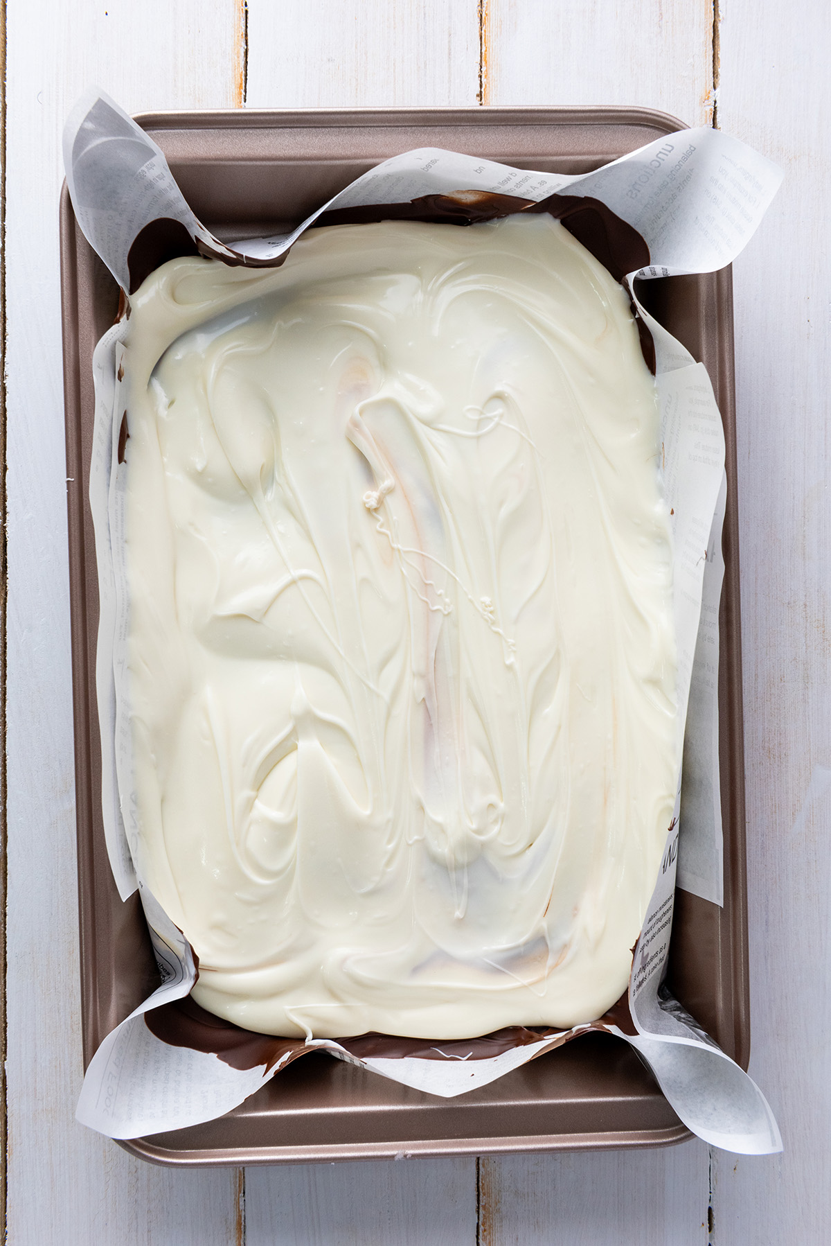 White chocolate spread over a layer of chocolate in parchment lined pan.