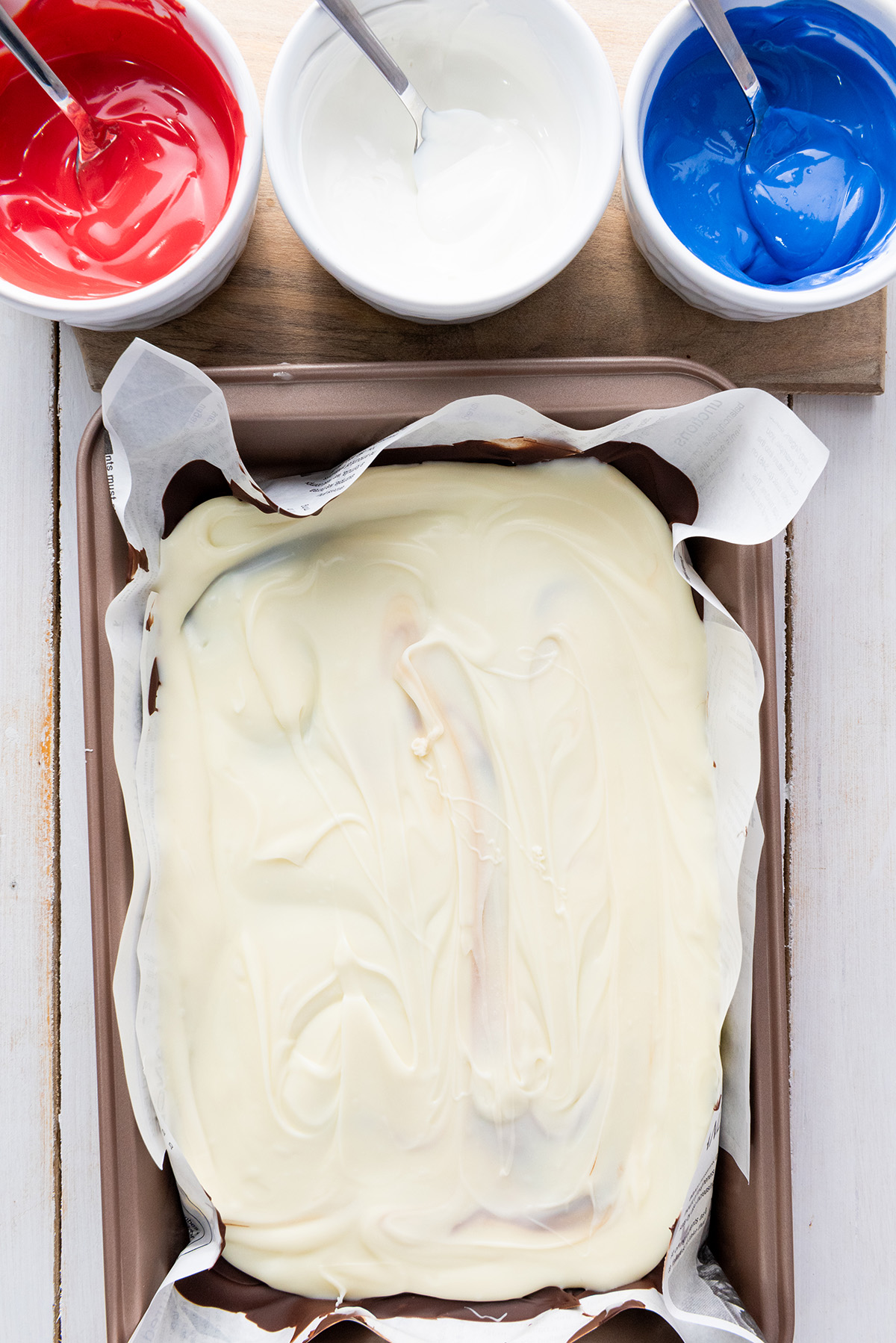 Showing hardened chocolate layers in a pan with melted red, white and blue candy melts.