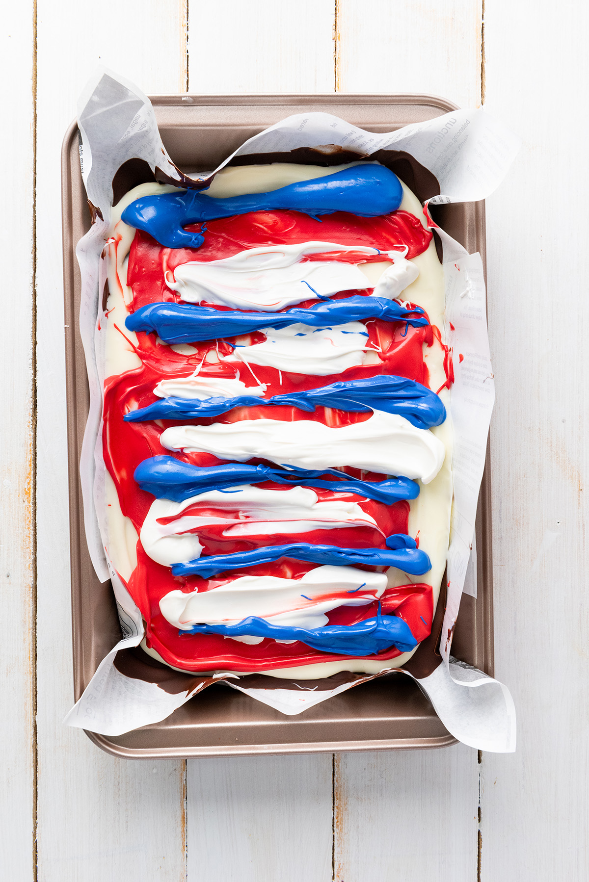 Swirling red, white and blue candy melts onto chocolate bark.
