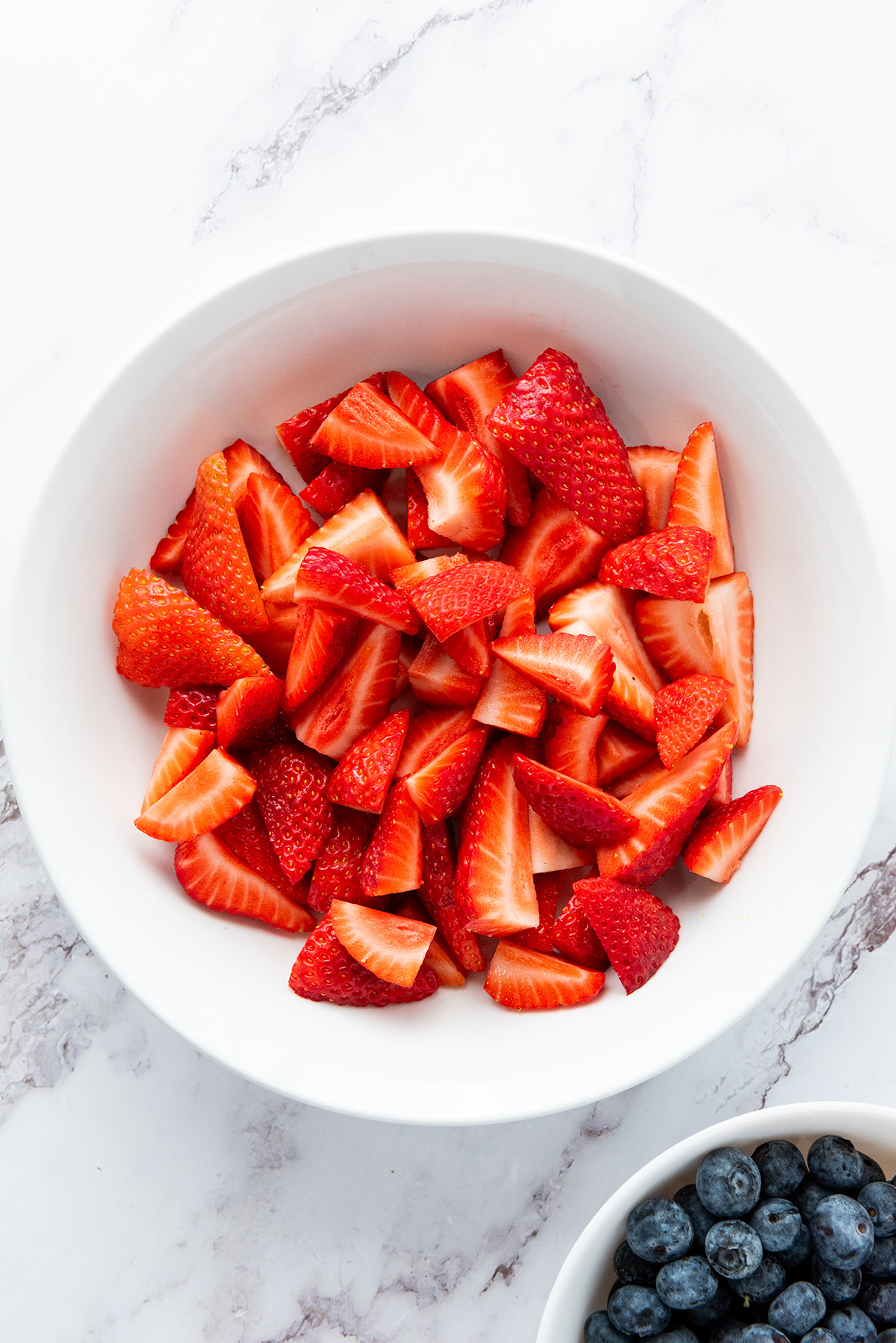Sliced strawberries in a white bowl.