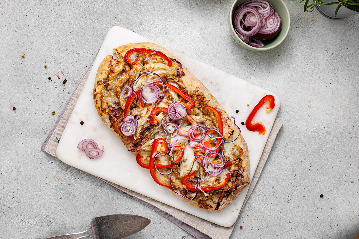 Fully baked BBQ chicken flatbread garnished with fresh cilantro, ready to slice and serve.