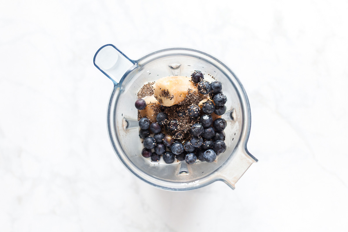 Frozen banana, blueberries, chia seeds, and cauliflower in a blender before making smoothie.
