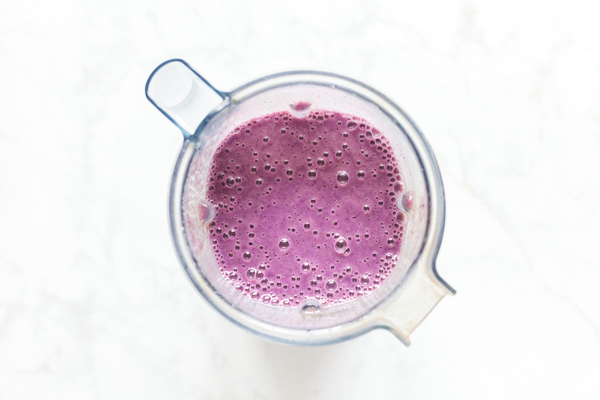 Freshly blended blueberry cauliflower smoothie in a blender pitcher ready to pour.