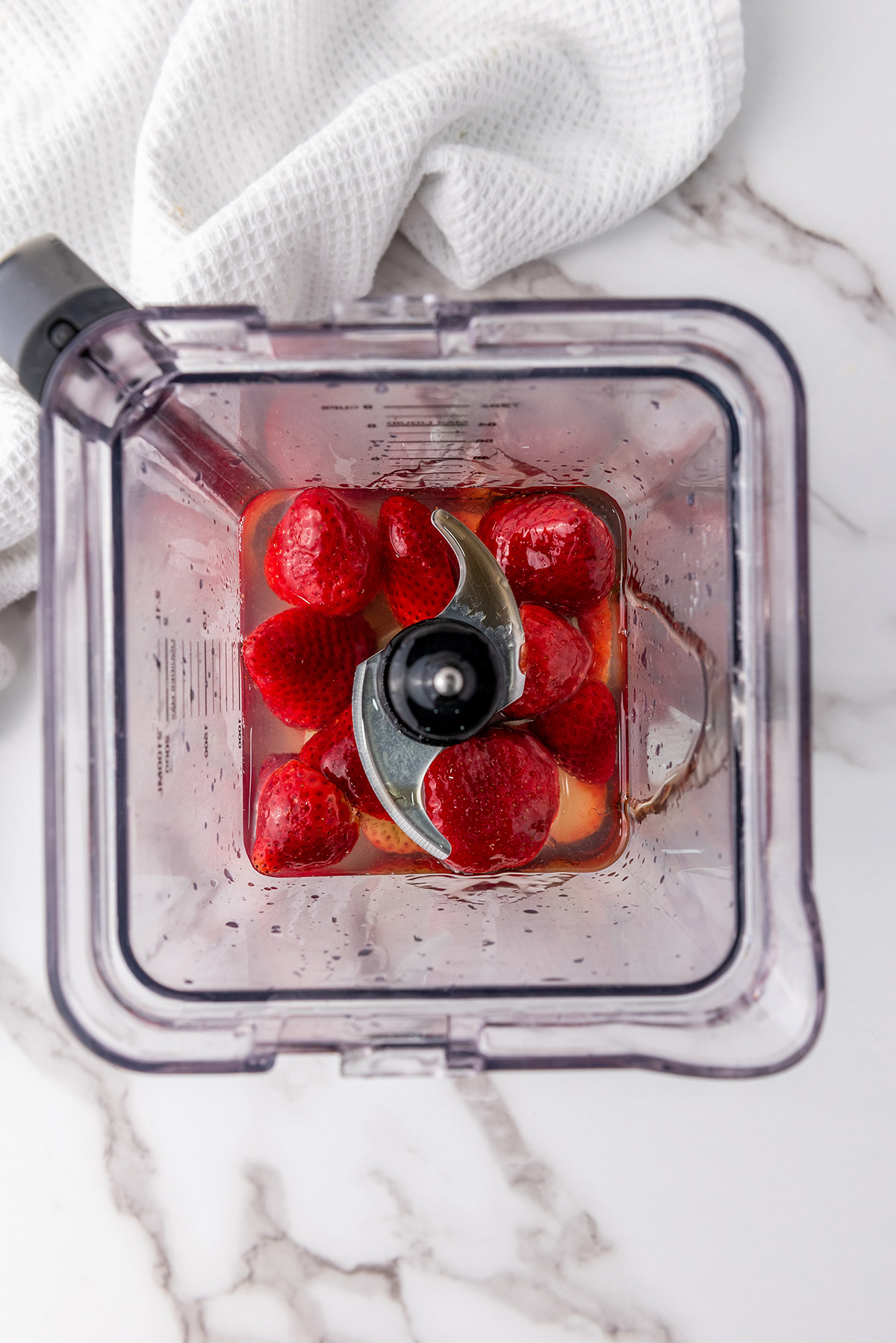 Fresh strawberries added to a blender, ready to be mixed with lemon juice and sweetener.