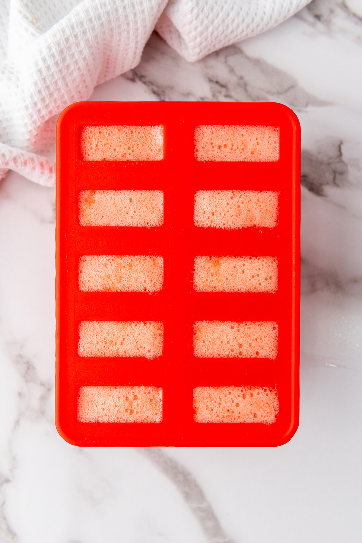 Strawberry lemonade mixture poured into popsicle molds.