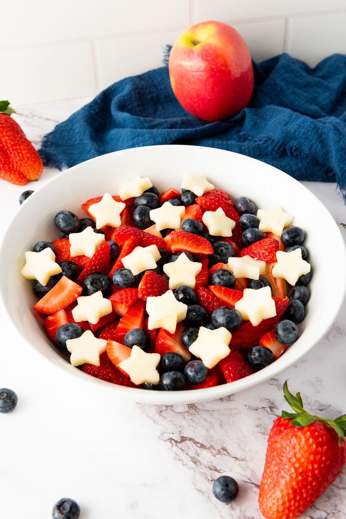 Overhead view of 4th of July fruit salad with strawberries, blueberries, and apple stars.