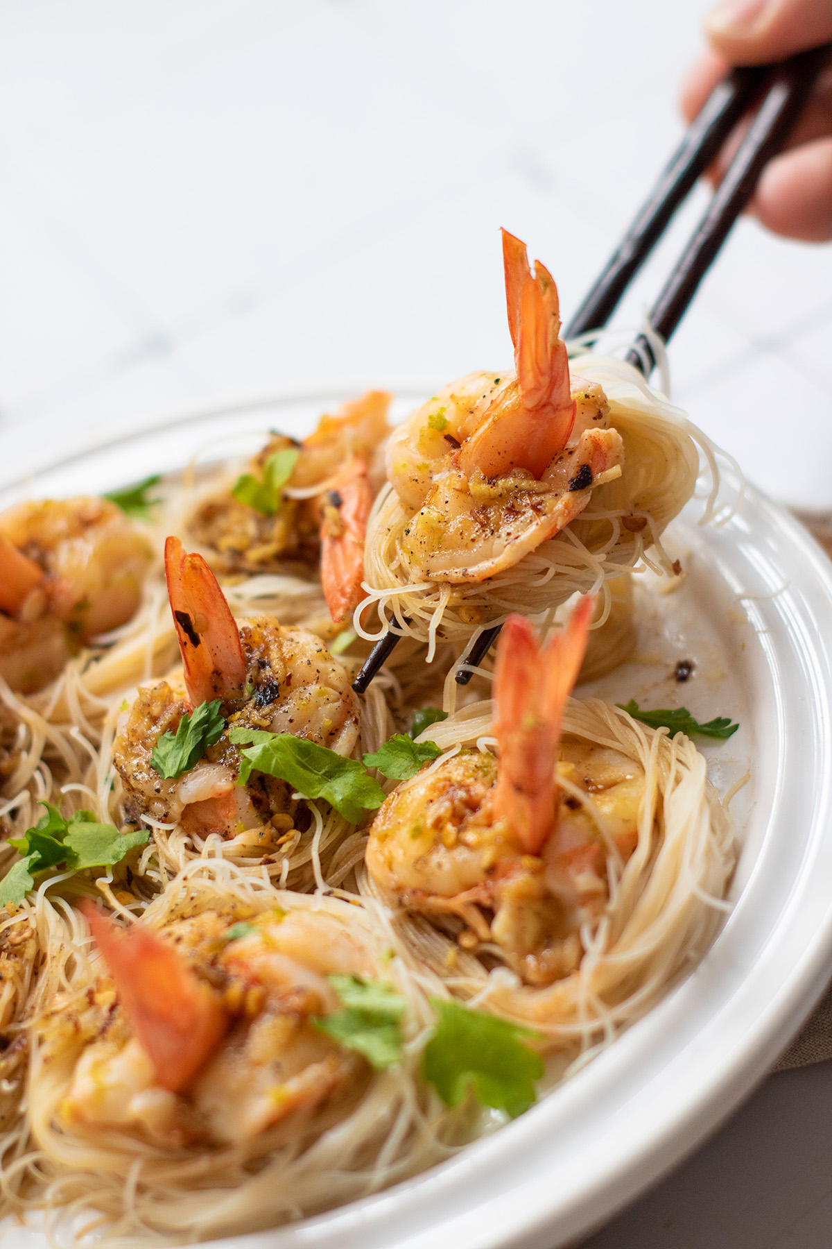 Garlic chili butter shrimp boats are quick, flavorful, and a little fancy. Juicy shrimp sit on vermicelli noodle nests that soak up every drop of the buttery garlic-chili sauce. Finished garlic chili shrimp boats with noodles, ready to serve on a plate with chopsticks and fresh cilantro.