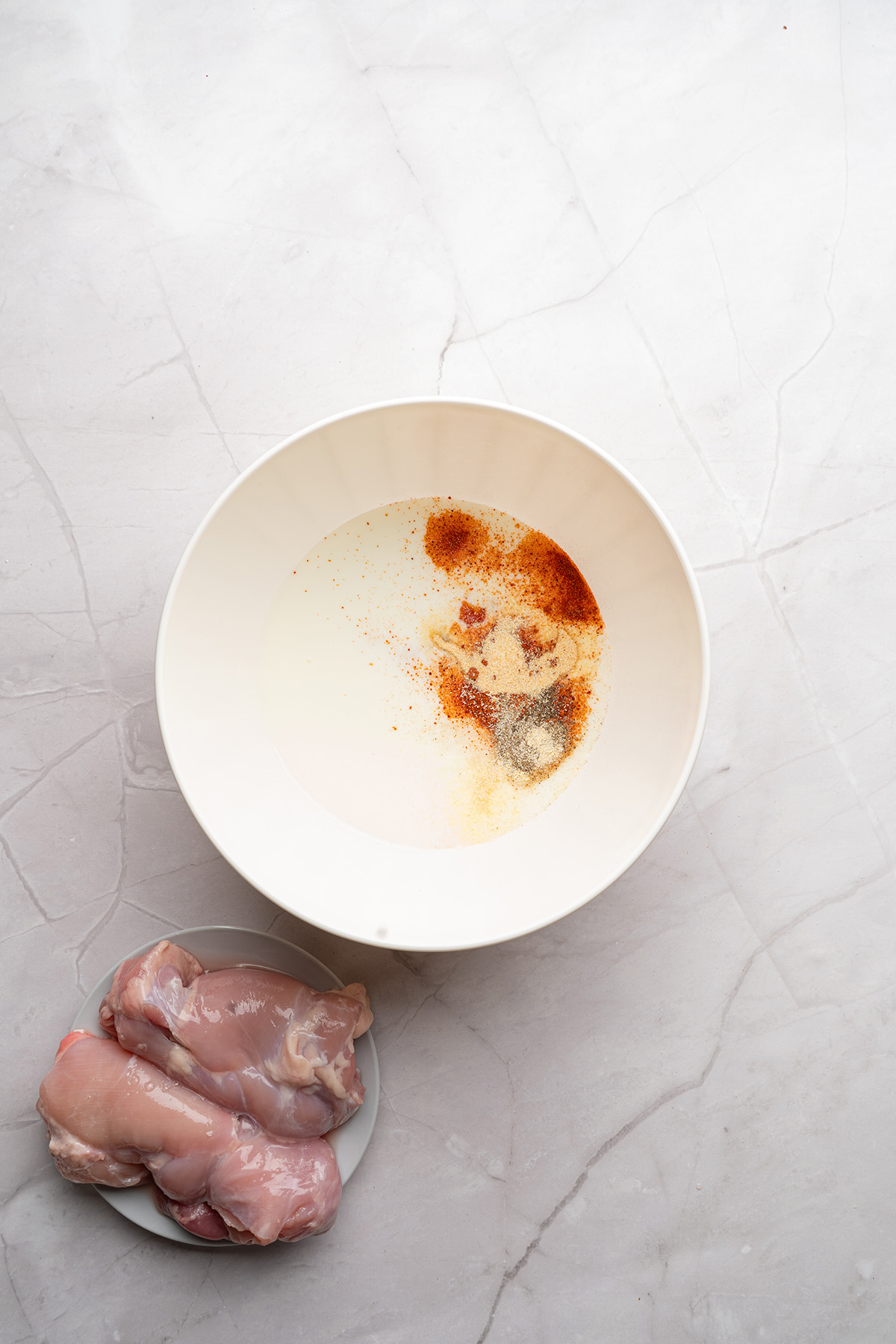 Buttermilk marinade in a mixing bowl with paprika, garlic powder, onion powder, pepper, and hot sauce.