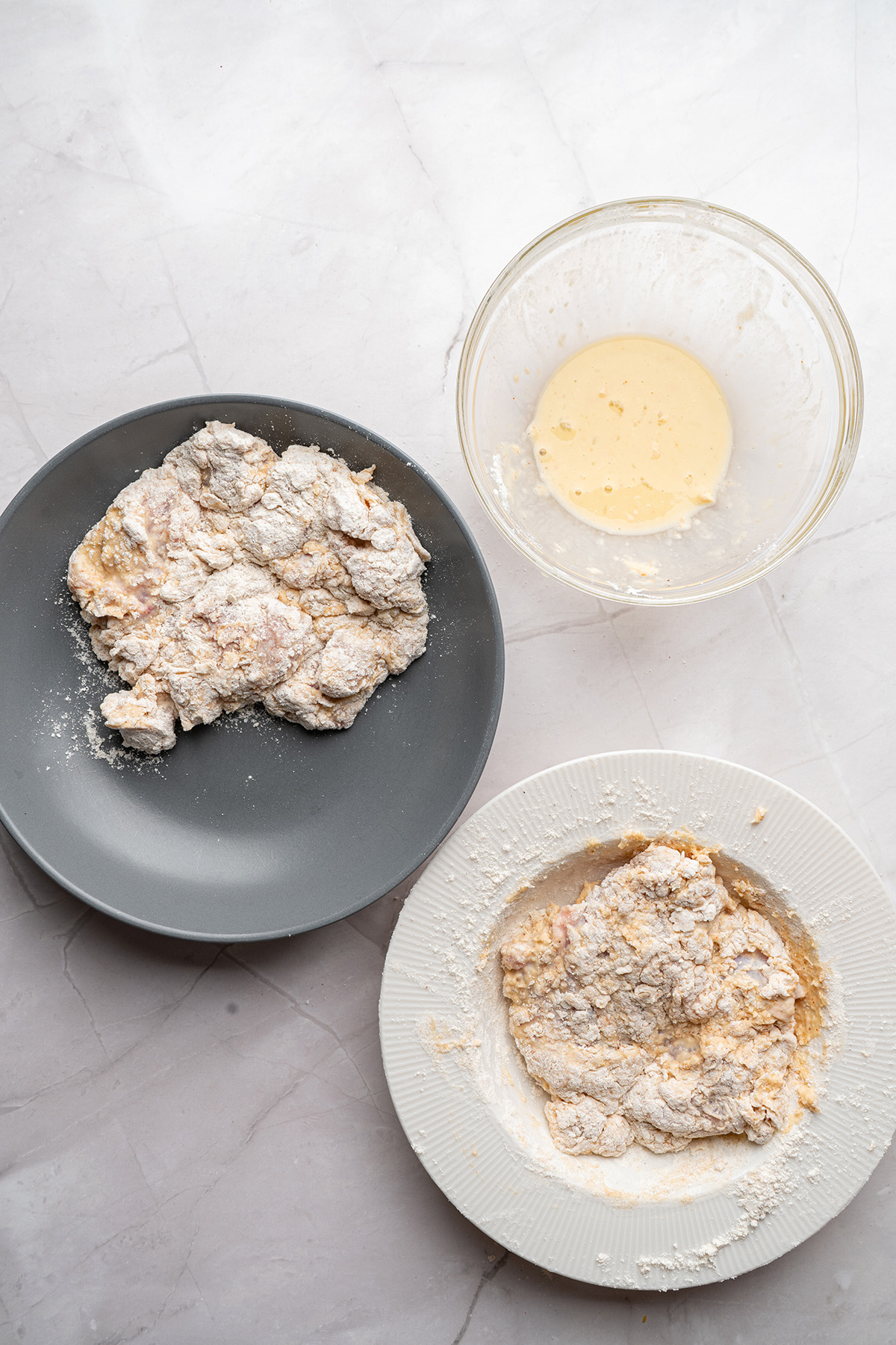 Marinated chicken pieces coated in seasoned flour, ready for frying.