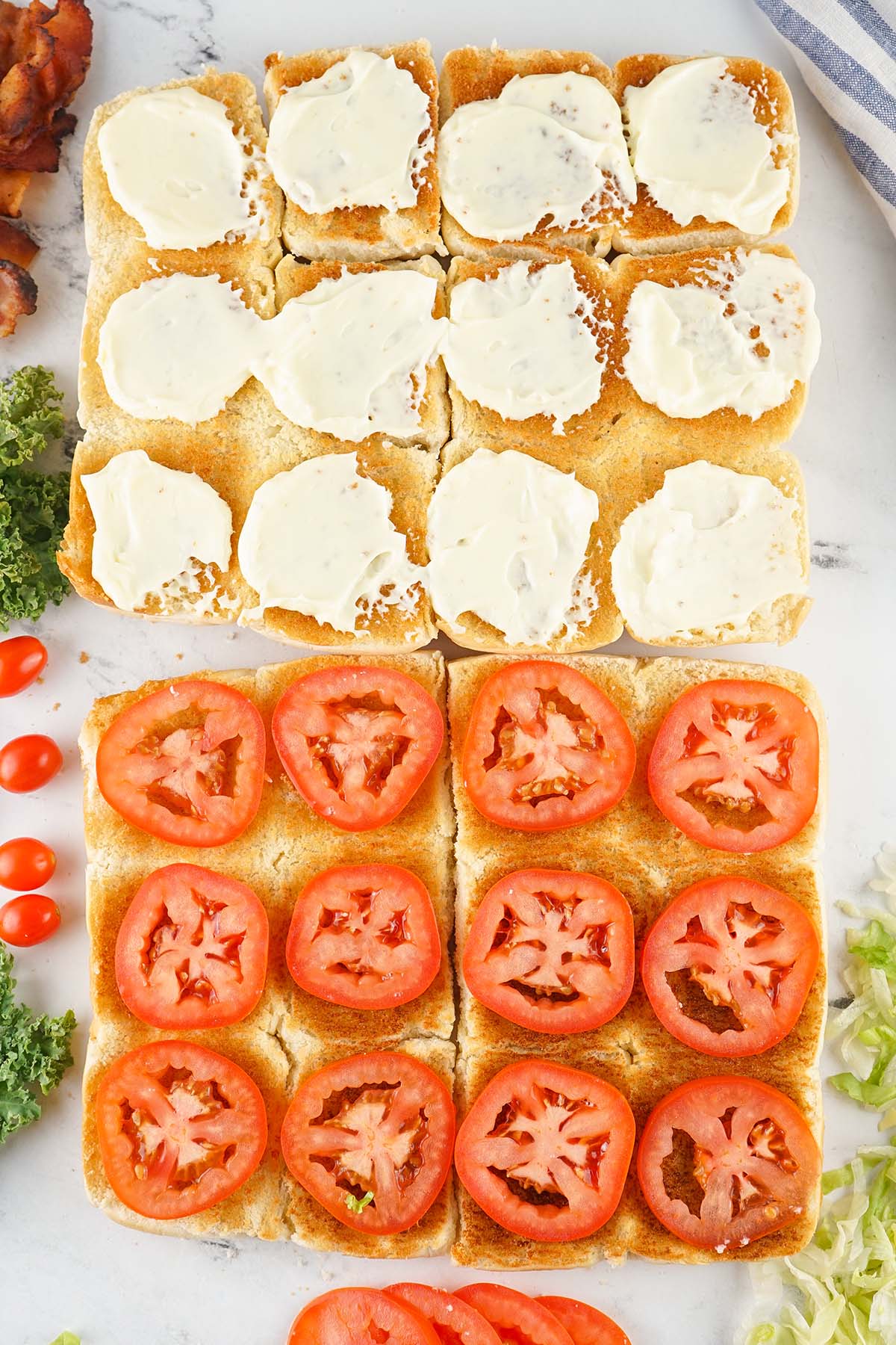 Slices of fresh tomato arranged evenly over the bottom buns, with mayo covered top buns in view.