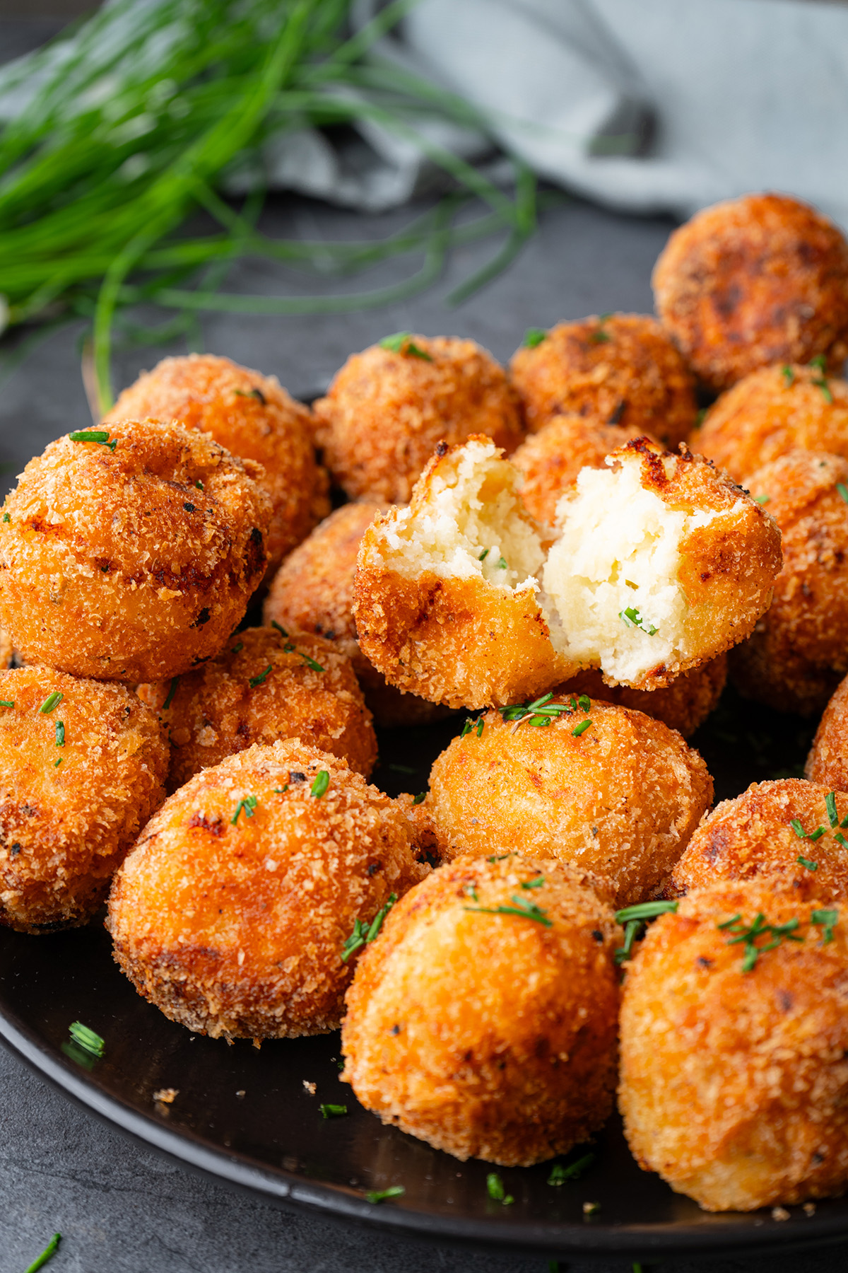 These fried mashed potato balls are crispy, golden, and loaded with cheesy flavor. The perfect way to turn leftover mashed potatoes into an irresistible side or snack. Close-up of a fried mashed potato ball broken in half, showing the soft, fluffy interior contrasted with the crispy golden crust.