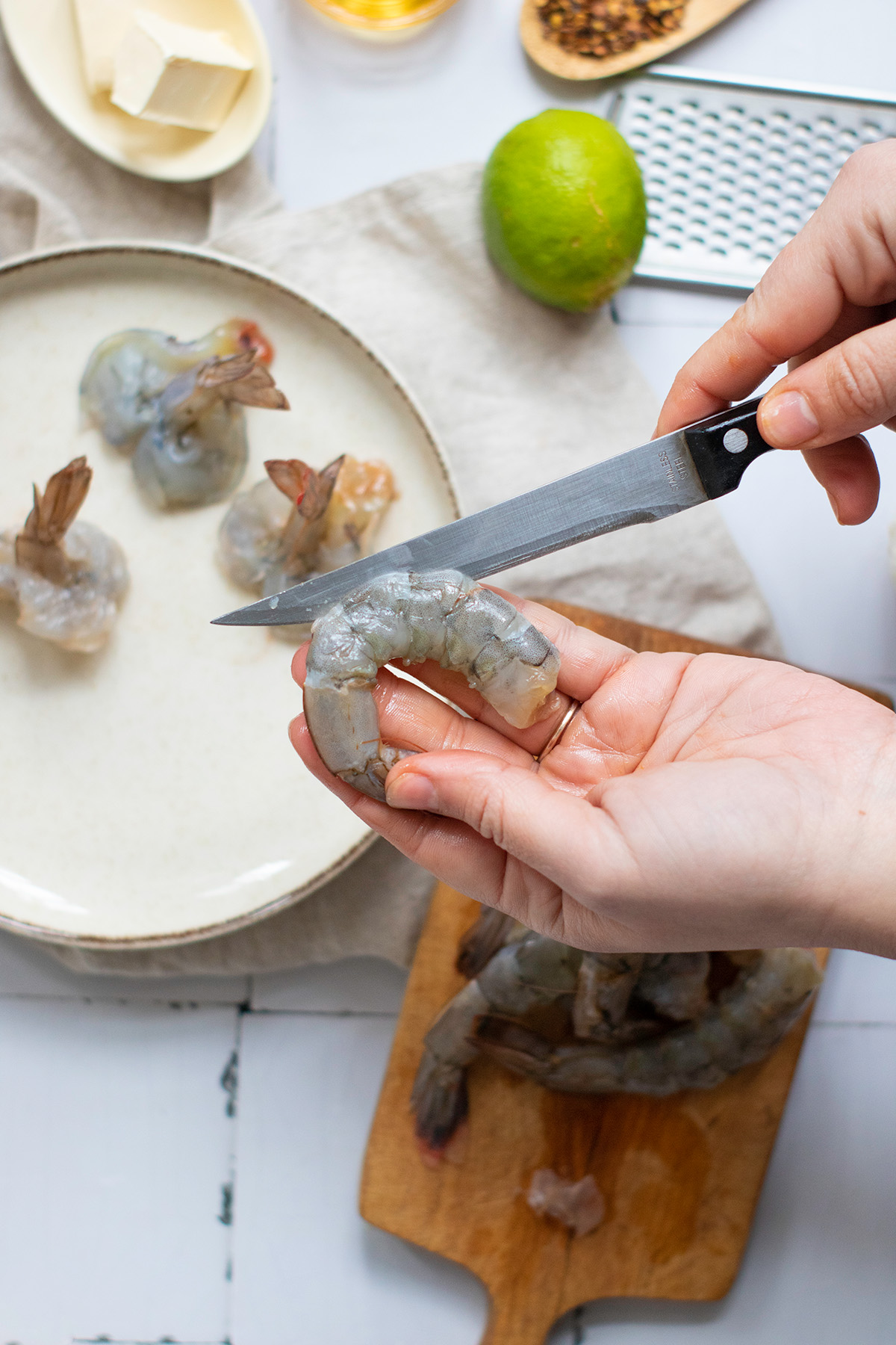Garlic chili butter shrimp boats are quick, flavorful, and a little fancy. Juicy shrimp sit on vermicelli noodle nests that soak up every drop of the buttery garlic-chili sauce. Step-by-step image of a hand slicing shrimp lengthwise to butterfly for shaping into shrimp boats.