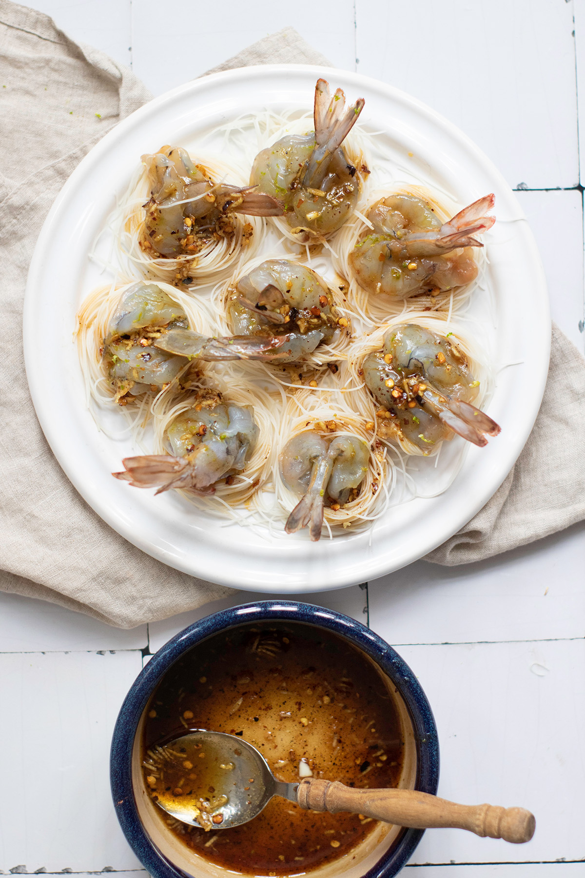 Garlic chili butter shrimp boats are quick, flavorful, and a little fancy. Juicy shrimp sit on vermicelli noodle nests that soak up every drop of the buttery garlic-chili sauce. Uncooked shrimp boats assembled with raw shrimp placed on noodle nests and drizzled with garlic chili butter.