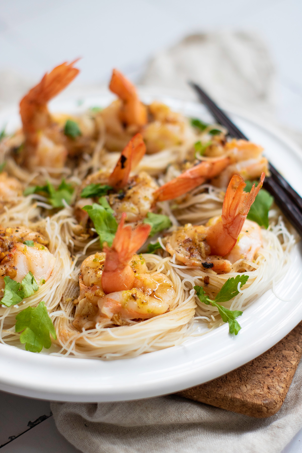 Close-up of cooked shrimp boats served on vermicelli nests and garnished with garlic chili butter and fresh herbs.