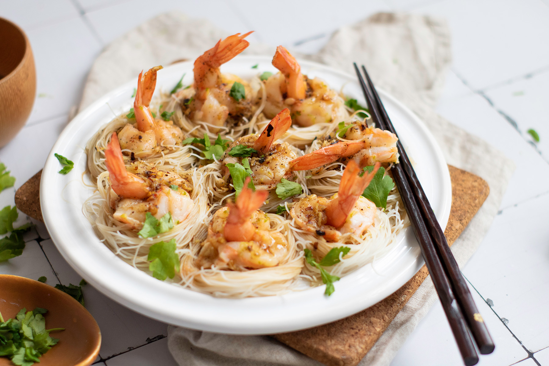 Garlic chili butter shrimp boats are quick, flavorful, and a little fancy. Juicy shrimp sit on vermicelli noodle nests that soak up every drop of the buttery garlic-chili sauce. Overhead view of steamed shrimp boats on a white platter, nestled on rice vermicelli and drizzled with chili garlic sauce.