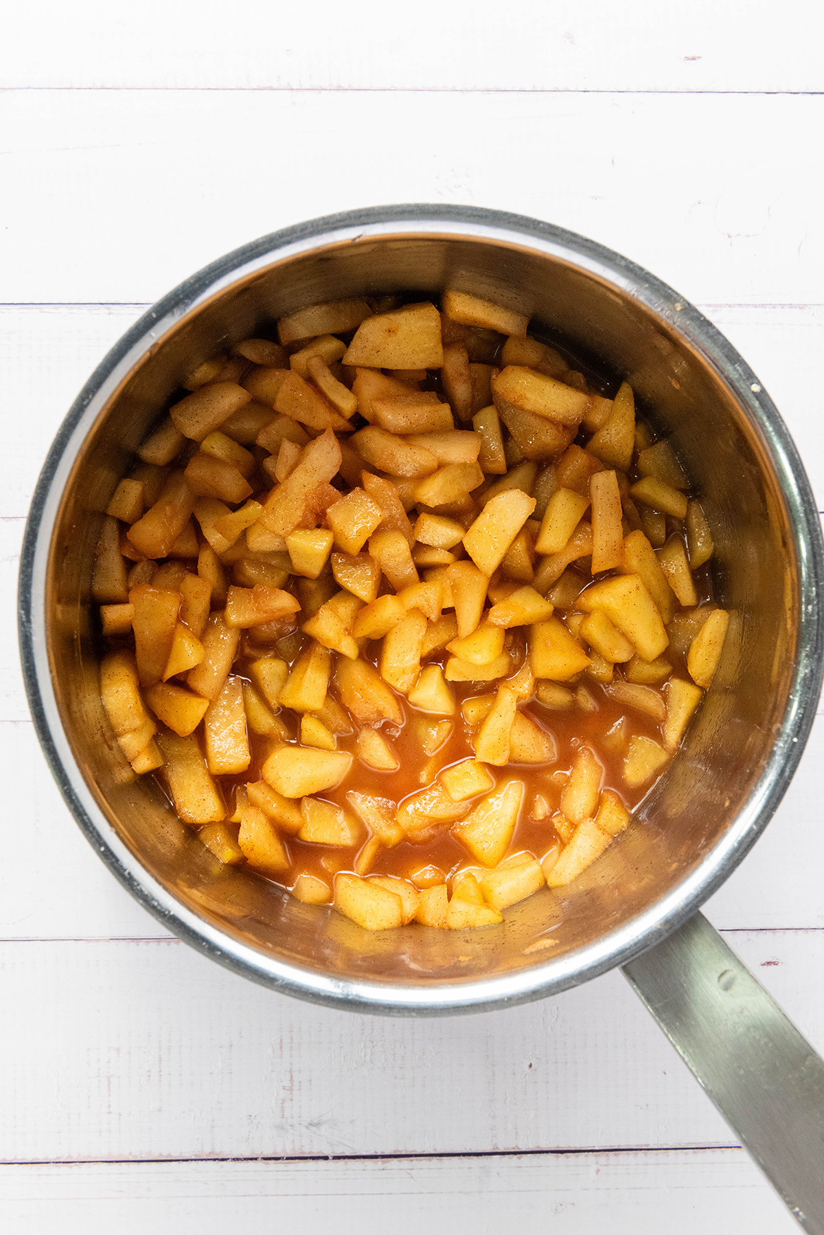 Cozy up with these easy apple hand pies made with flaky store-bought crust and a sweet cinnamon filling. All the comfort of homemade apple pie in an easy grab-and-go treat. Homemade apple filling with cinnamon and sugar simmering in a saucepan for apple hand pies.