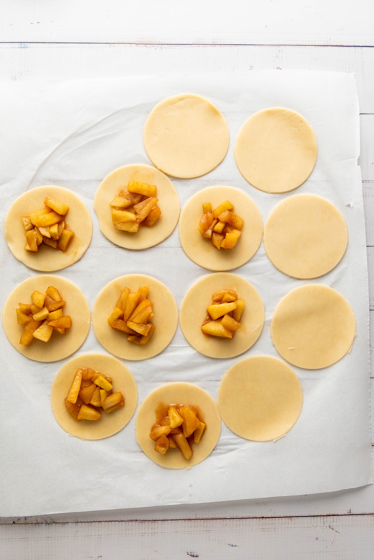 Cozy up with these easy apple hand pies made with flaky store-bought crust and a sweet cinnamon filling. All the comfort of homemade apple pie in an easy grab-and-go treat. Unbaked apple hand pies with spiced apple filling placed on round dough circles.