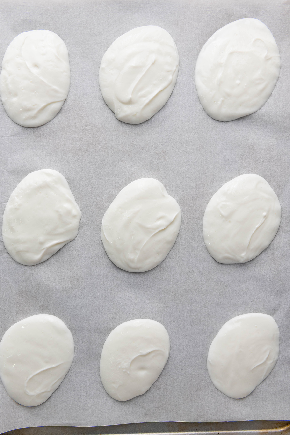 Cool, creamy, and topped with fresh fruit and crunchy granola, this frozen Greek yogurt bark is an easy, healthy treat you can make in minutes. Plain dollops of Greek yogurt spread on a parchment-lined baking sheet, ready for toppings.