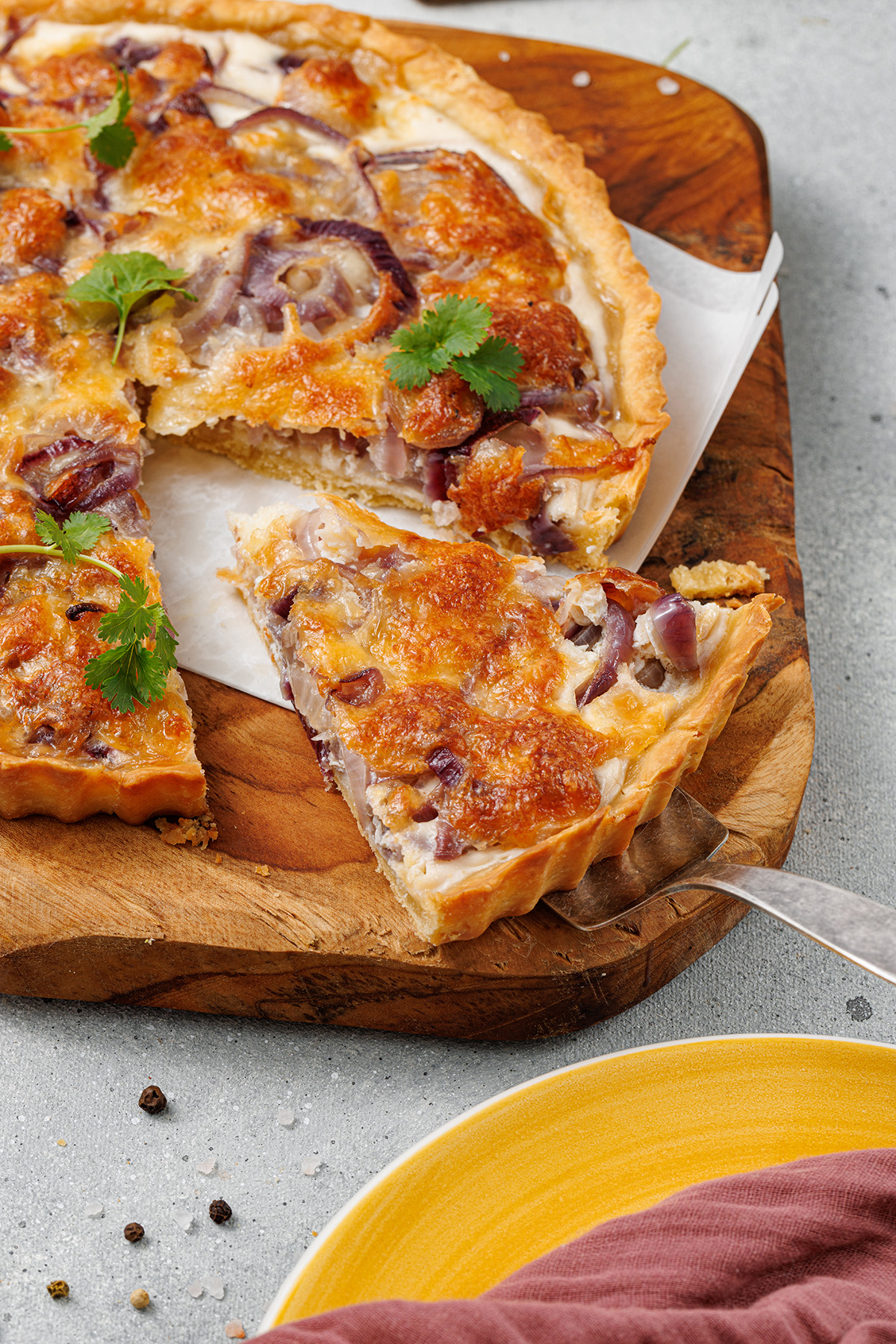 Flaky pastry, sweet caramelized onions and a creamy egg and Gruyere cheese filling make this onion tart both flavorful and irresistible to serve as an appetizer, dinner or even brunch. A caramelized onion tart with a golden cheese topping, being sliced to reveal its rich onion filling inside the flaky crust.