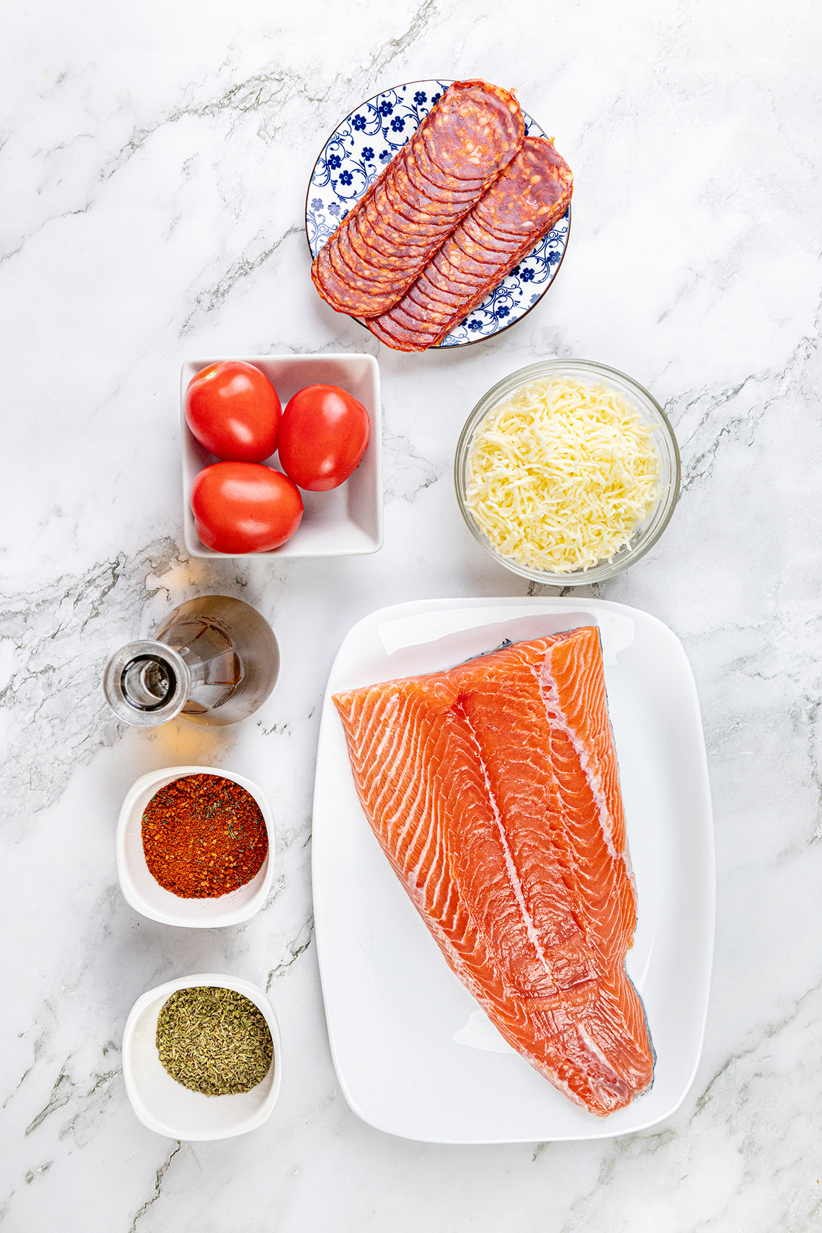 Chilean salmon, chorizo, mozzarella cheese, tomatoes and seasonings on the counter.