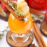 Overhead view of Fireball apple cider cocktail with apple slice, rosemary sprig, cinnamon stick, and star anise.
