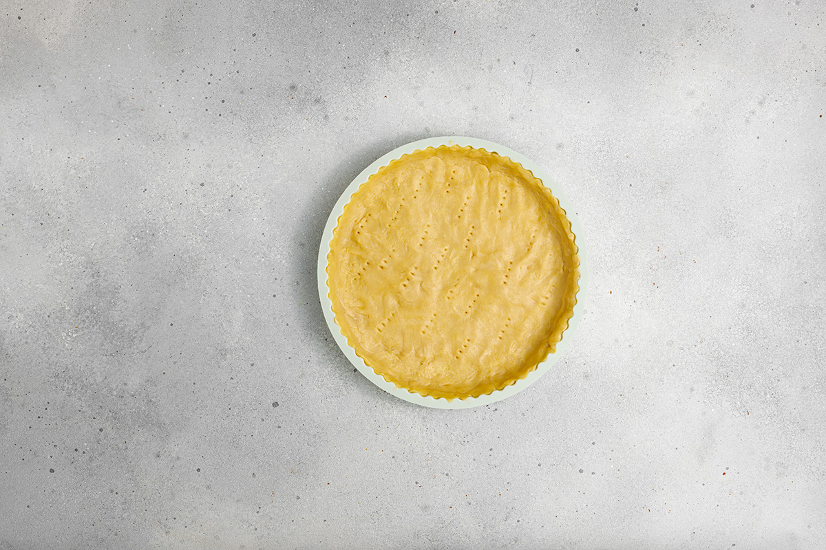 Flaky pastry, sweet caramelized onions and a creamy egg and Gruyere cheese filling make this onion tart both flavorful and irresistible to serve as an appetizer, dinner or even brunch. Tart crust dough rolled and pressed into a fluted tart pan, with fork pricks in the base for blind baking.