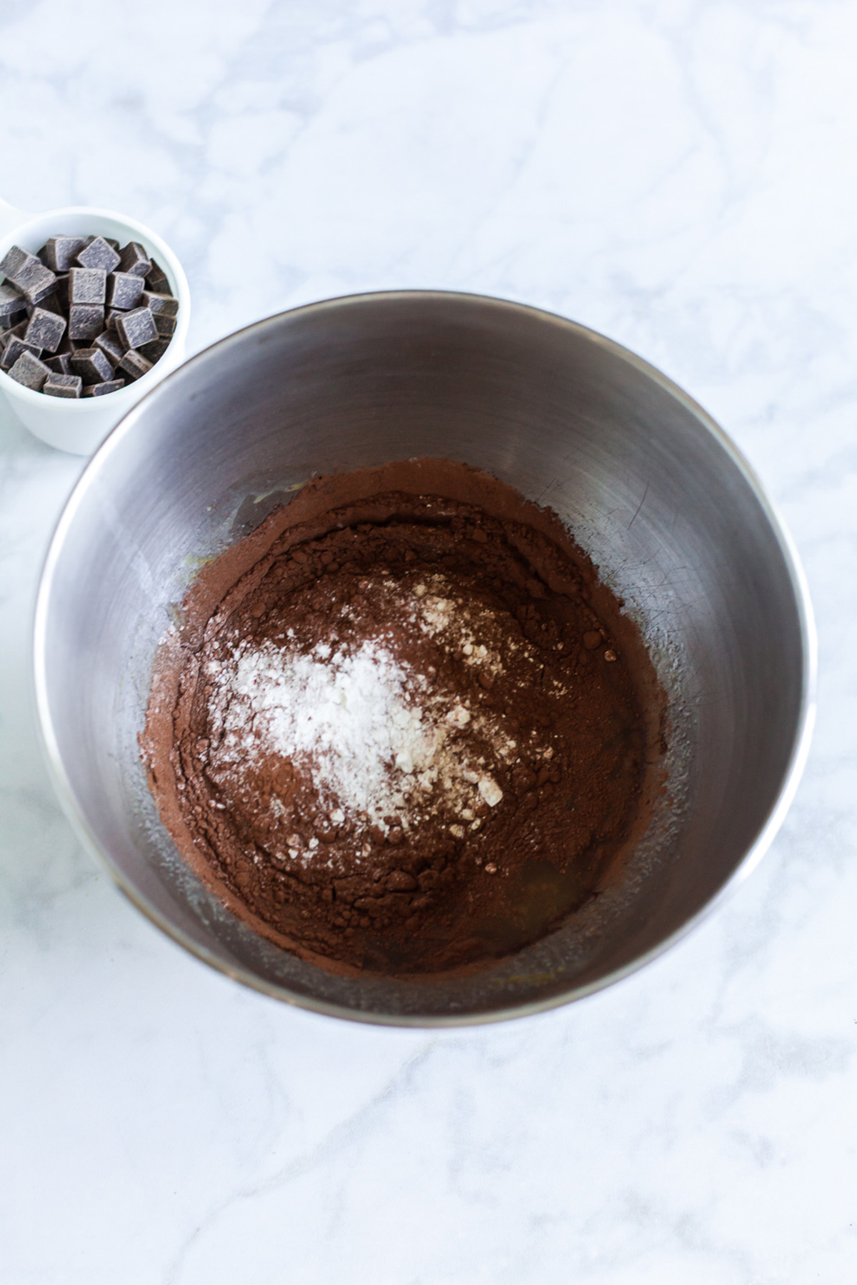 Part brownie, part cake, these brownie cakes are rich like a fudgy brownie but baked in cupcake form and made completely from scratch. Cocoa powder, flour, and salt added into the wet mixture in a stand mixer bowl.