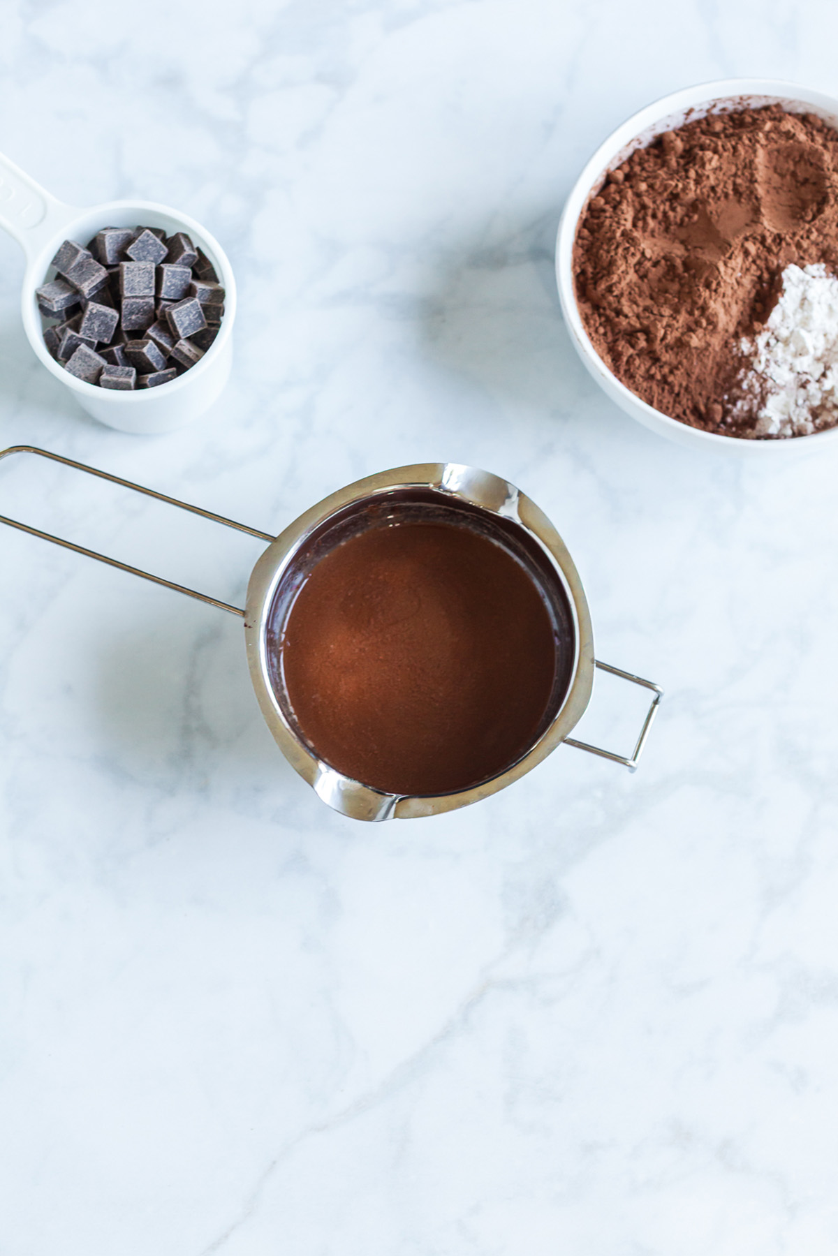 Part brownie, part cake, these brownie cakes are rich like a fudgy brownie but baked in cupcake form and made completely from scratch. Melted butter and chopped dark chocolate combined into a smooth mixture in a small saucepan.
