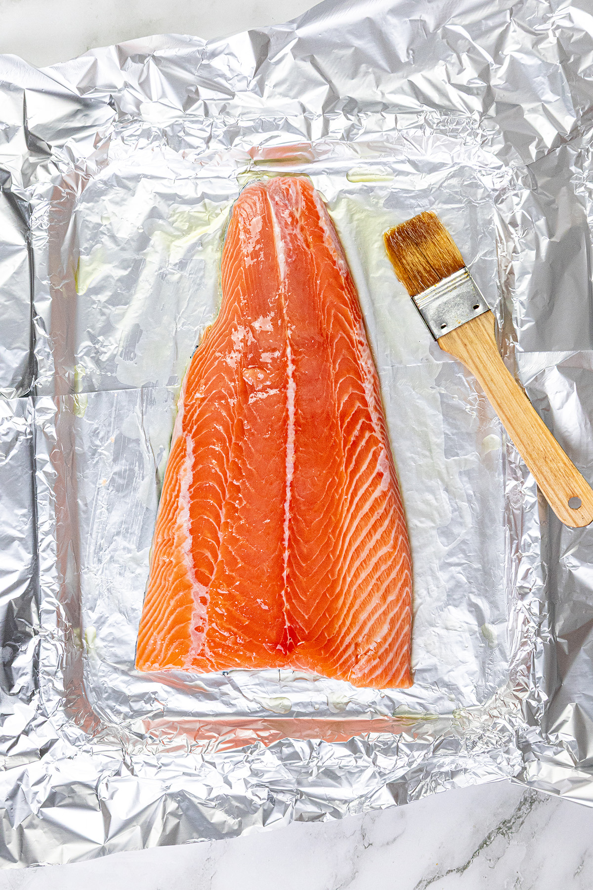 Brushing Chilean salmon with olive oil.