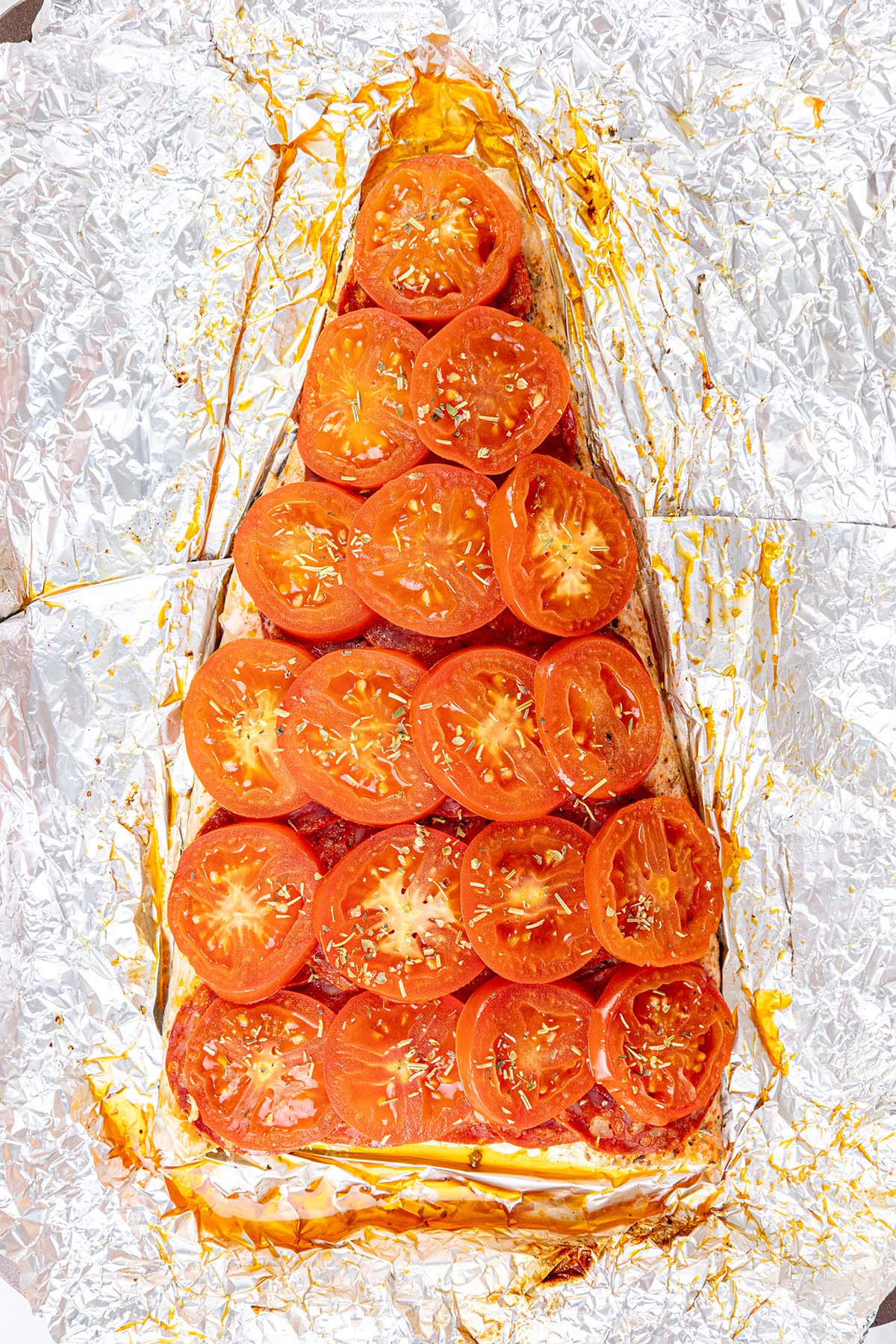 Baked Chilean salmon unwrapped from foil showing the cooked tomatoes. 