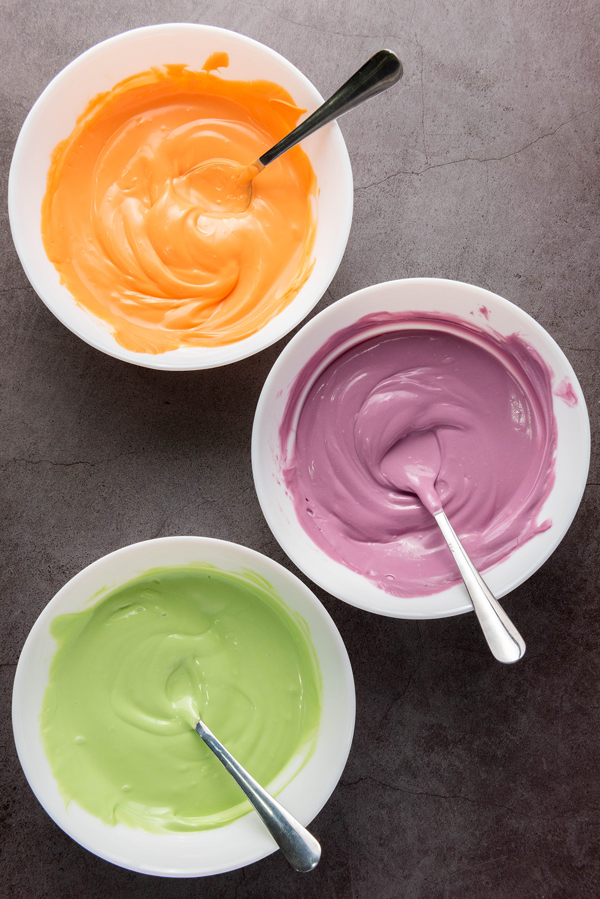 These chocolate covered Halloween Oreos are the easiest spooky treat! Dip, decorate, and serve a colorful no-bake treat that’s just as fun to decorate as it is to eat! Three bowls of melted candy coating in green, purple, and orange, ready for dipping.